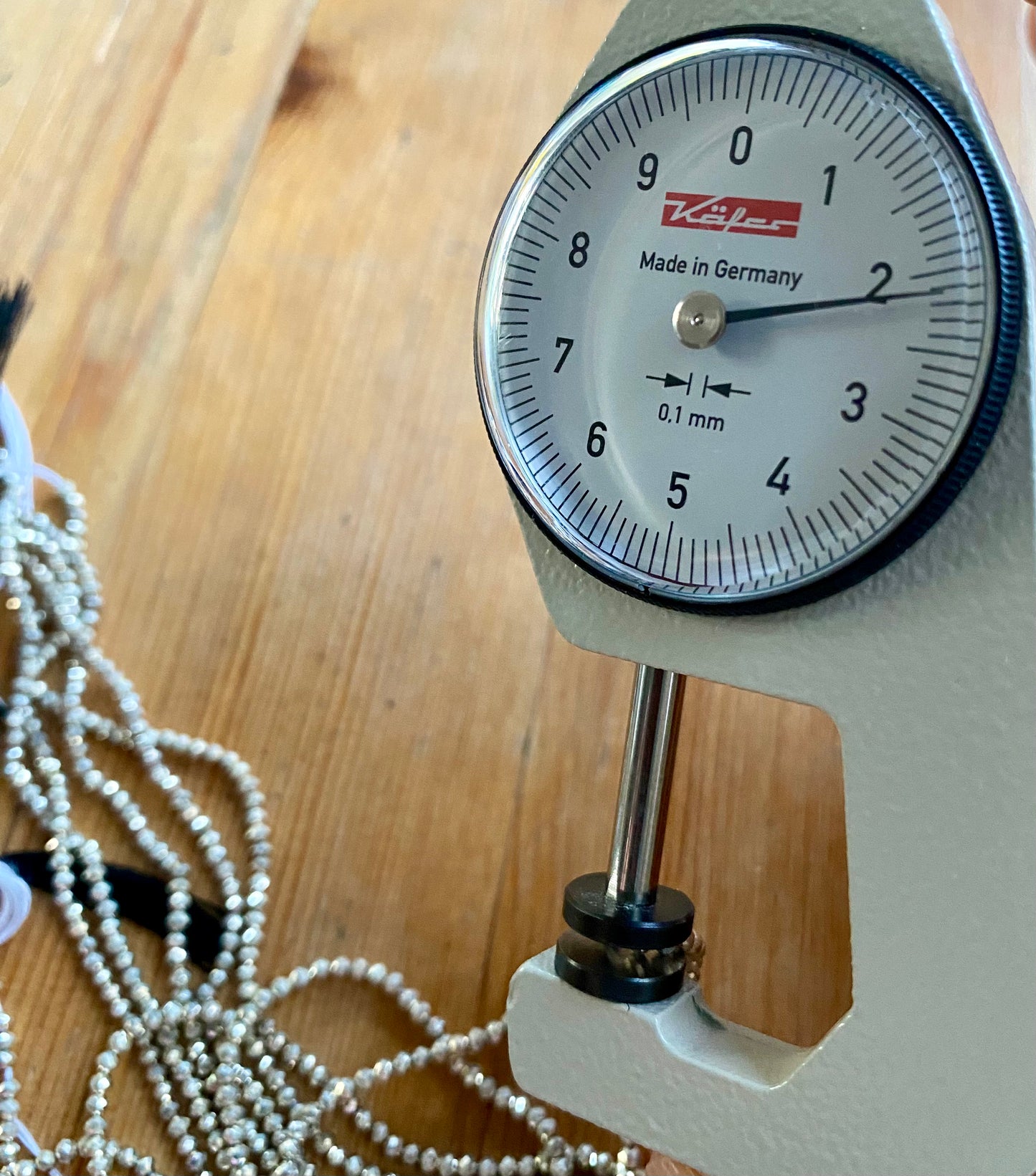 A dial gauge measures the Sliver Pyrite Faceted Rondelle 2.2mm  gemstone.