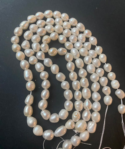  A beautiful strand of 6.5mm freshwater smooth baroque pearl beads resting on a sleek black background, showcasing their lustre.