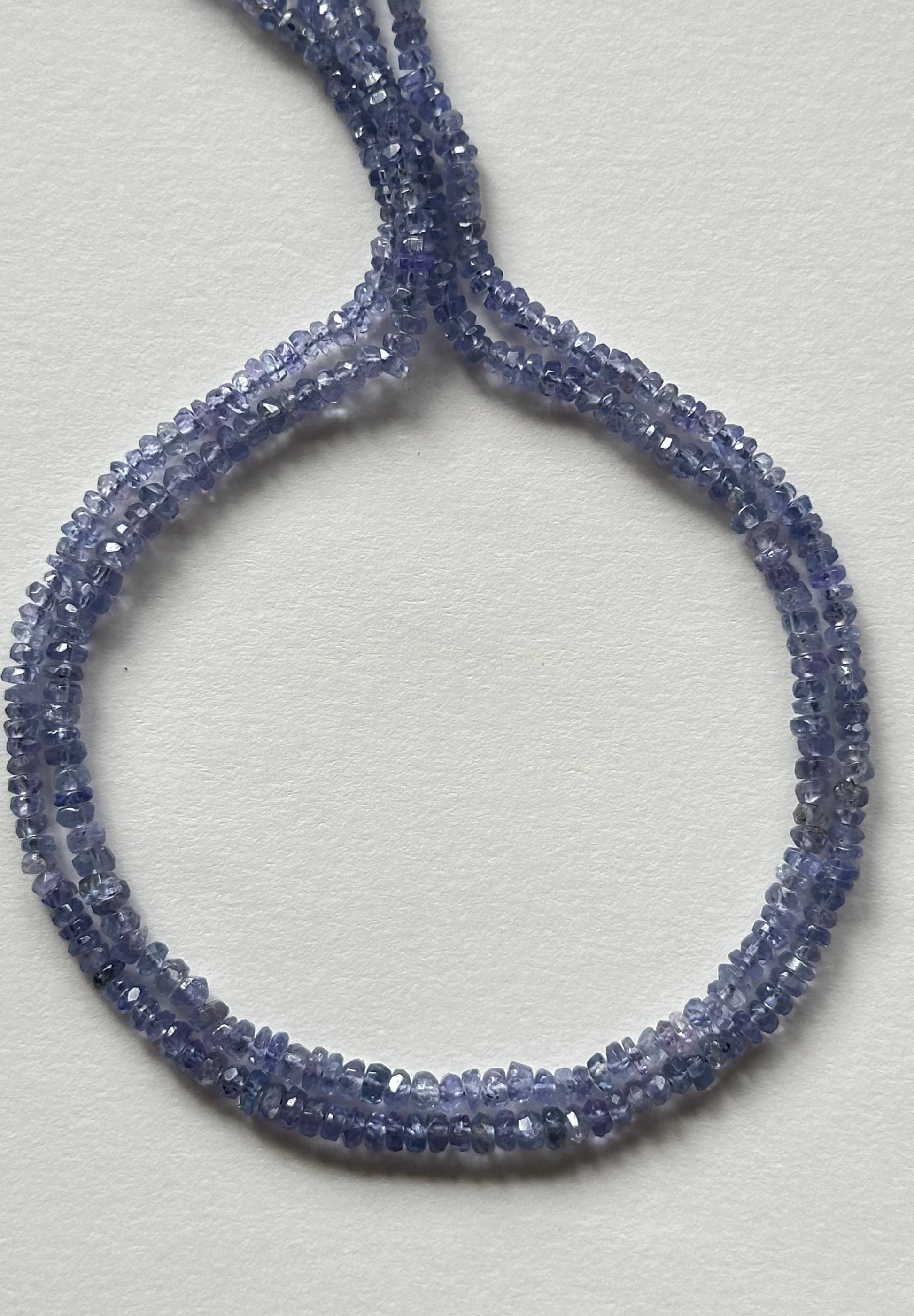 Strands of faceted blue Tanzanite rondelle gemstone beads, measuring 2.4mm to 3mm, showcasing their vibrant colour and shine.