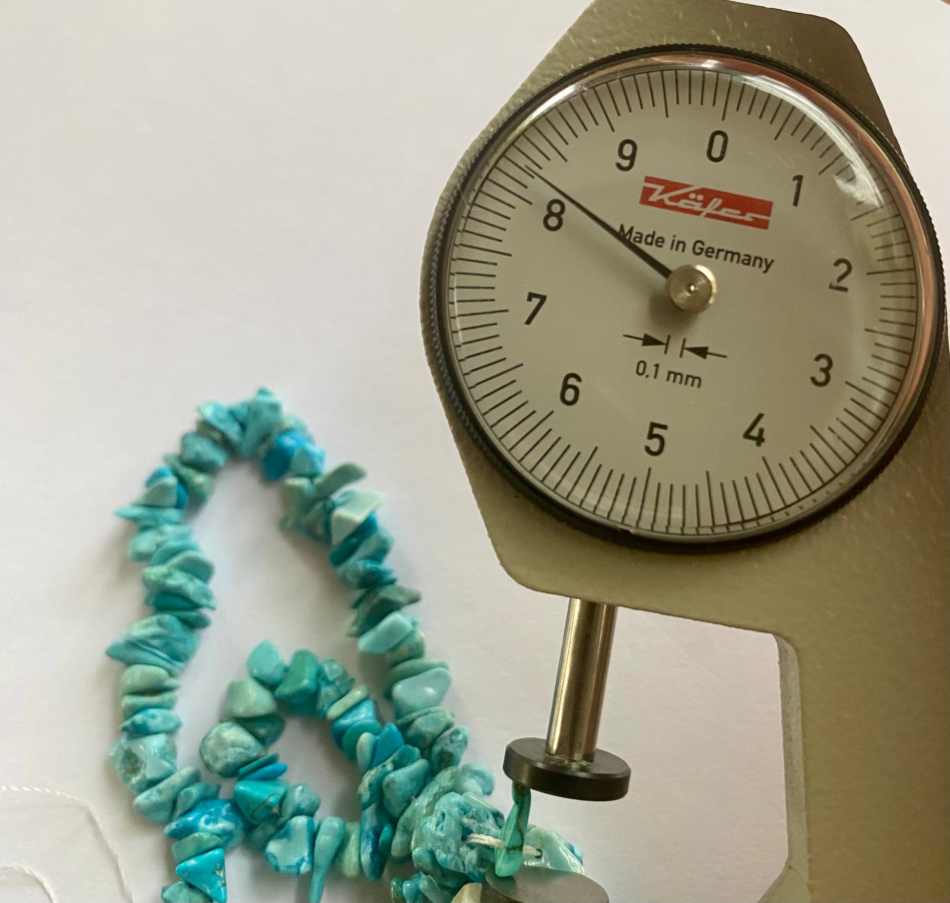 A dial gauge measures the Turquoise Chips Uncut Chips  5-8mm  gemstone.