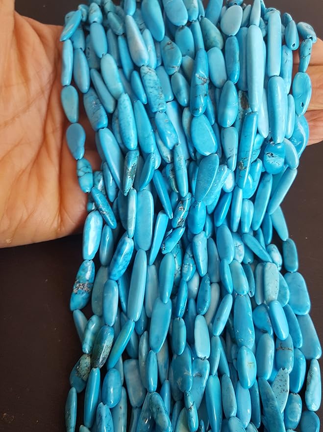 A hand holds a vibrant bunch of smooth blue turquoise stone beads, ranging from 6mm to 8mm in size.