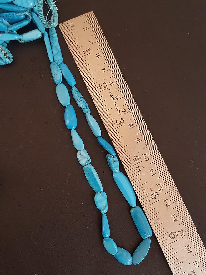  A blue turquoise stand made of smooth, tumble beads, with a ruler beside it for size reference. 