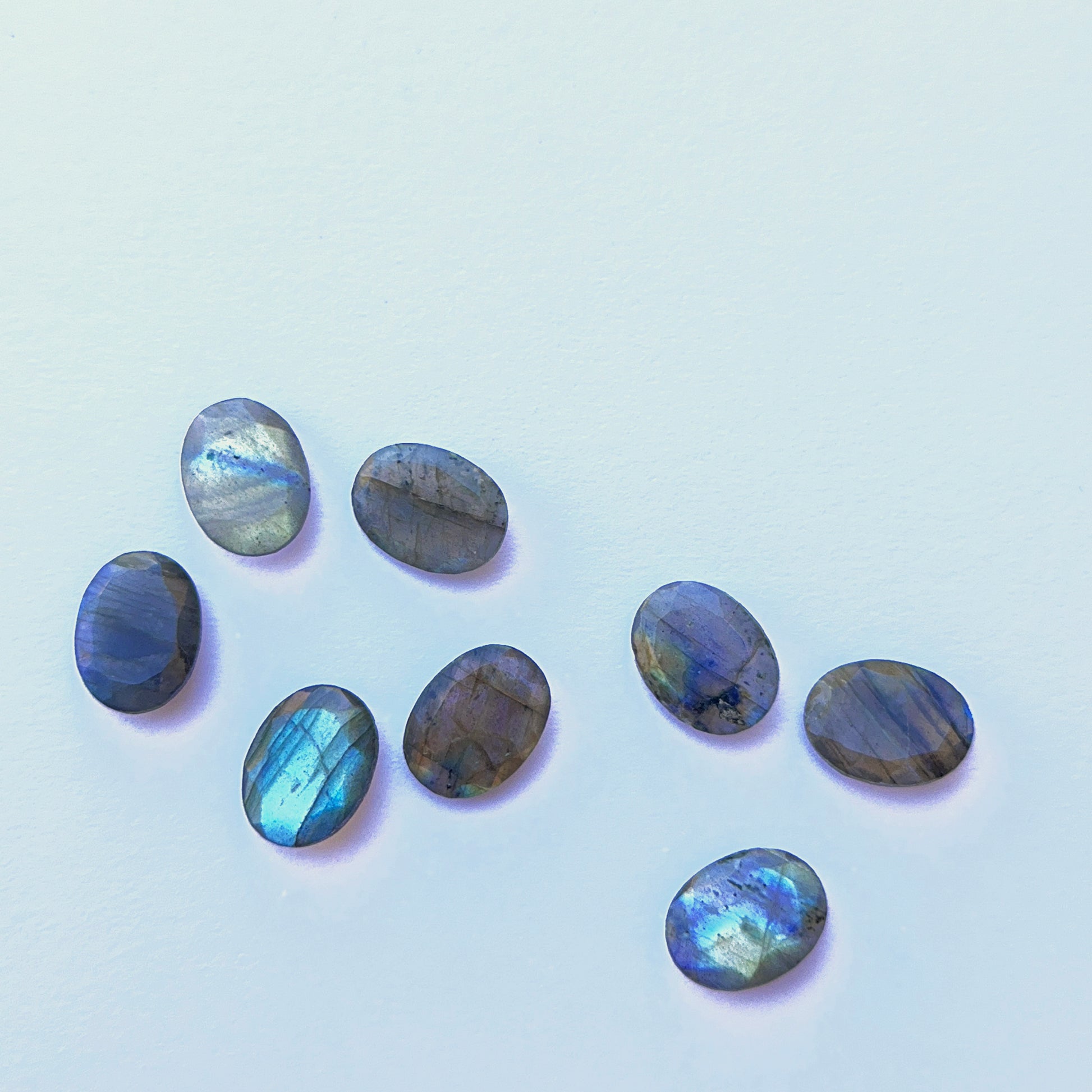 Labradorite oval cabochon displayed under light showing labradorescence, smooth dome and premium stone quality.