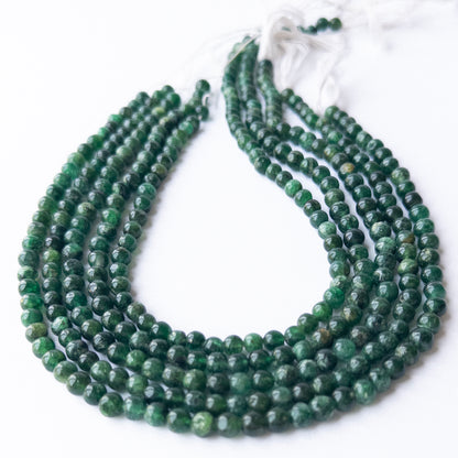 Strands of Aventurine smooth round gemstone beads arranged neatly, showcasing their smooth finish and gentle green hues.