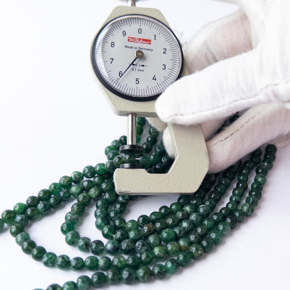 A dial gauge measures the Aventurine smooth round 5.7–5.9mm gemstone bead.