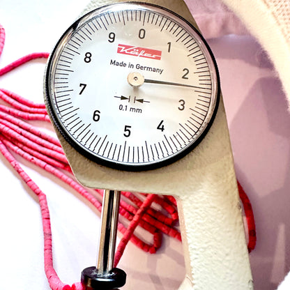 A dial gauge measures the Afghan Tube Shaped Heishi 2.3- 2.4mm gemstone.