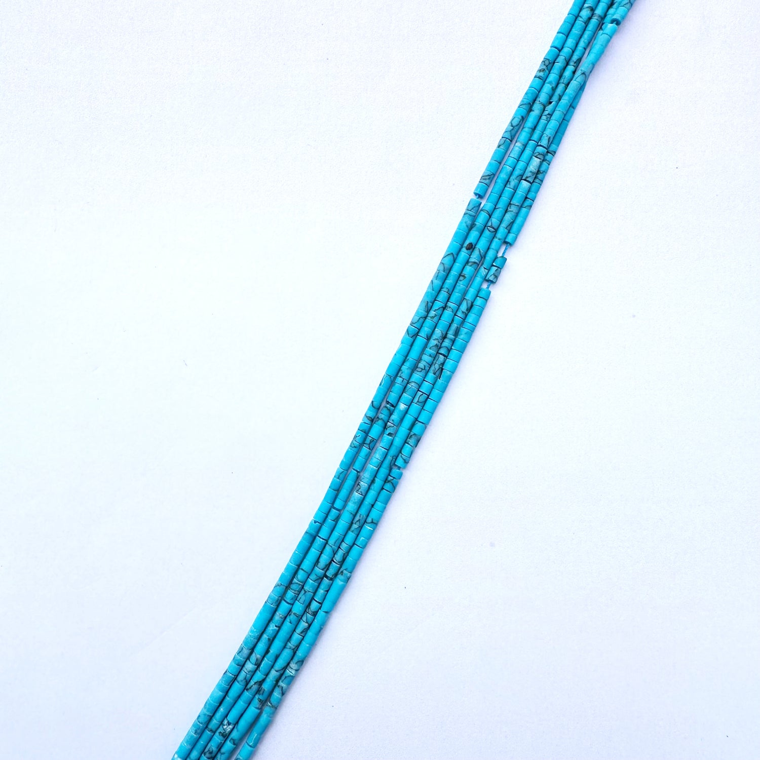 Afghan Tube Heishi beads in blue tones aligned on a 32cm strand.