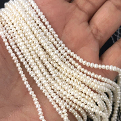 A person holds delicate strands of freshwater pearl beads, showcasing their smooth design.