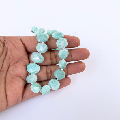 A person holds delicate strands of Amazonite faceted briolette beads, showcasing their cut design.