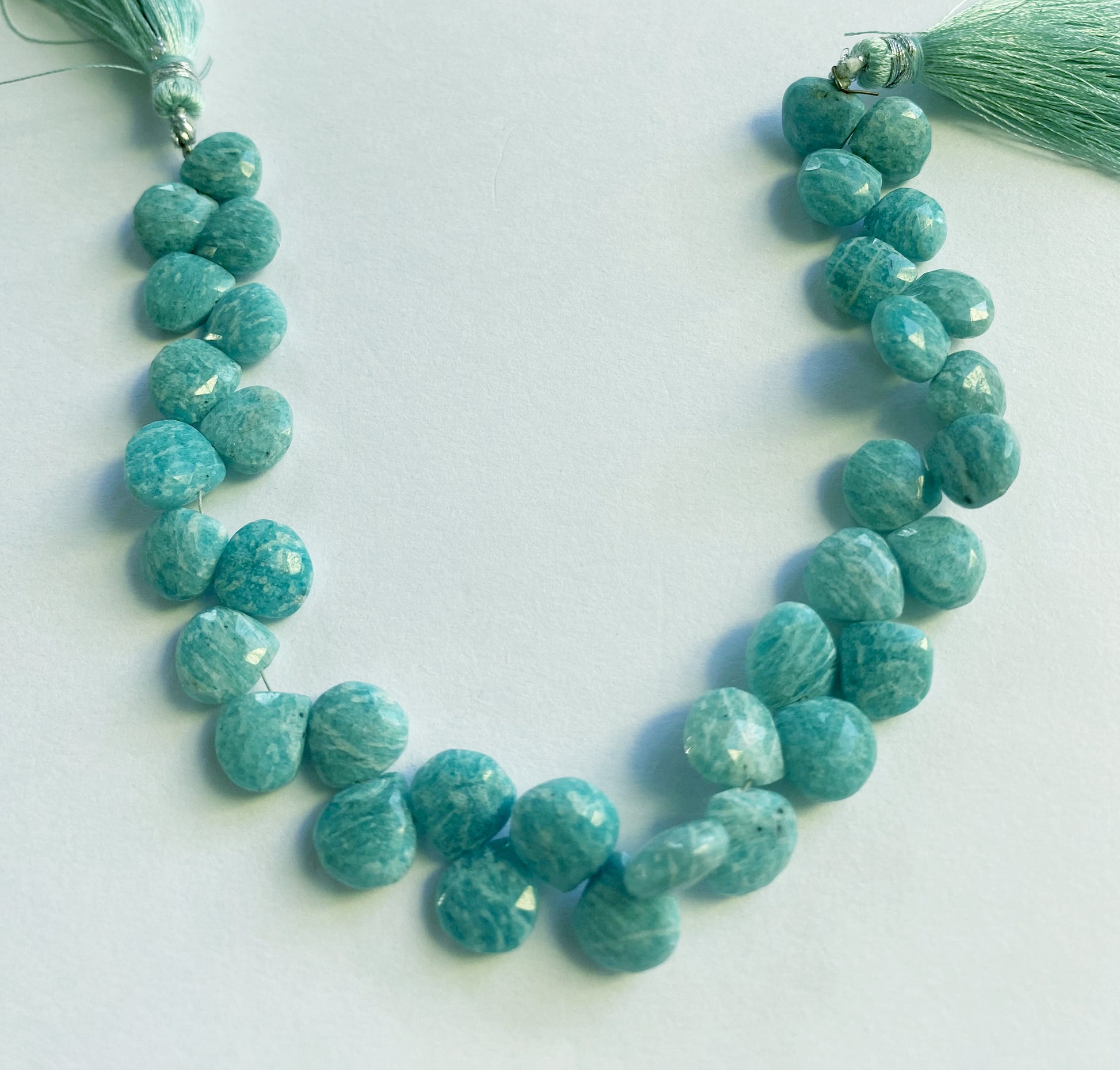 Close-up view of 9.5–10mm Amazonite heart beads, showing lustrous shine and precision-cut facets. 