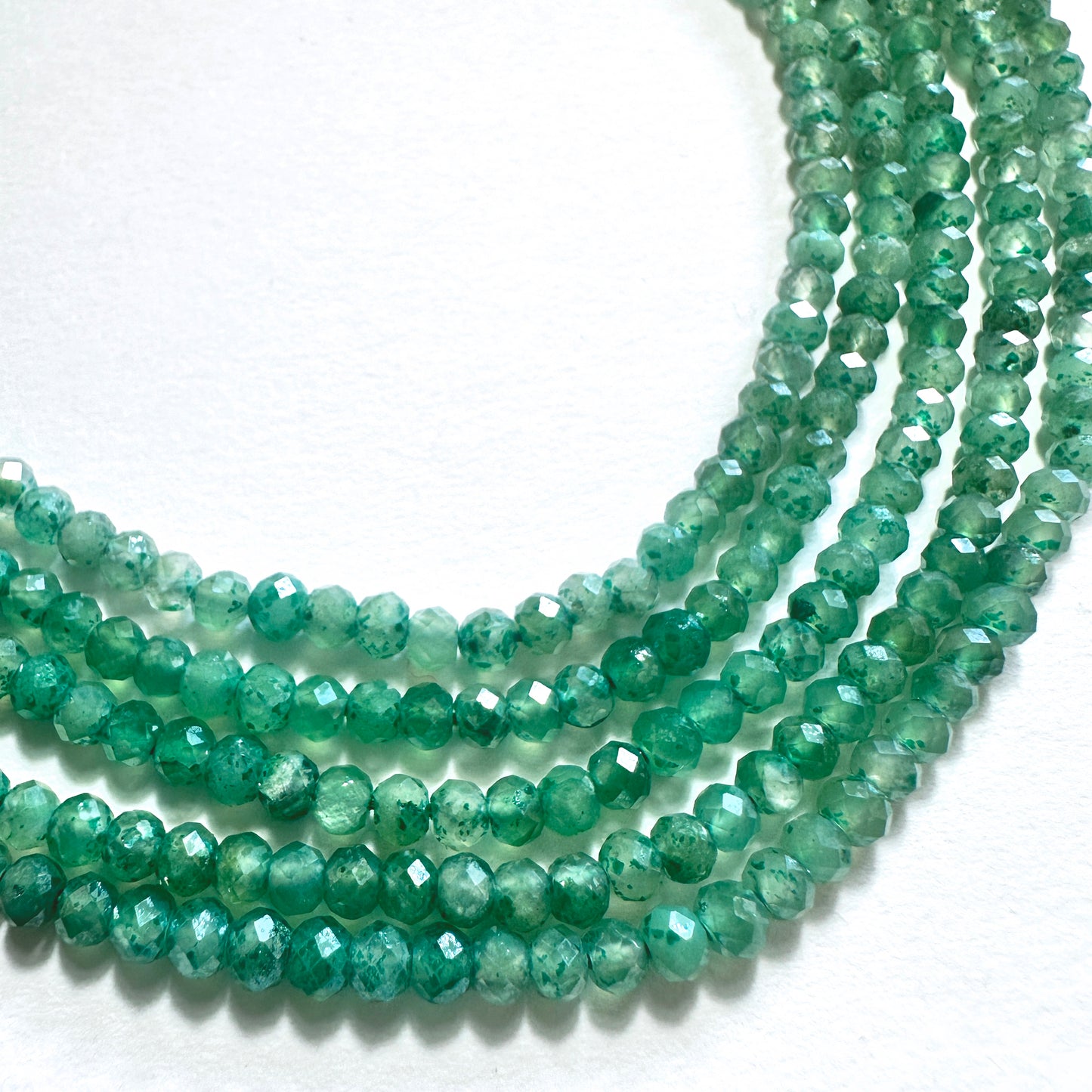 Close-up of green quartz rondelle beads with faceted cuts and consistent 3-3.5mm sizing.