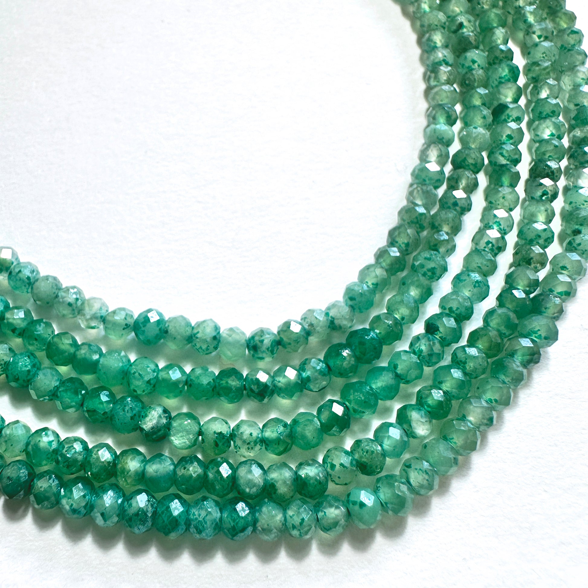 Close-up of green quartz rondelle beads with faceted cuts and consistent 3-3.5mm sizing.