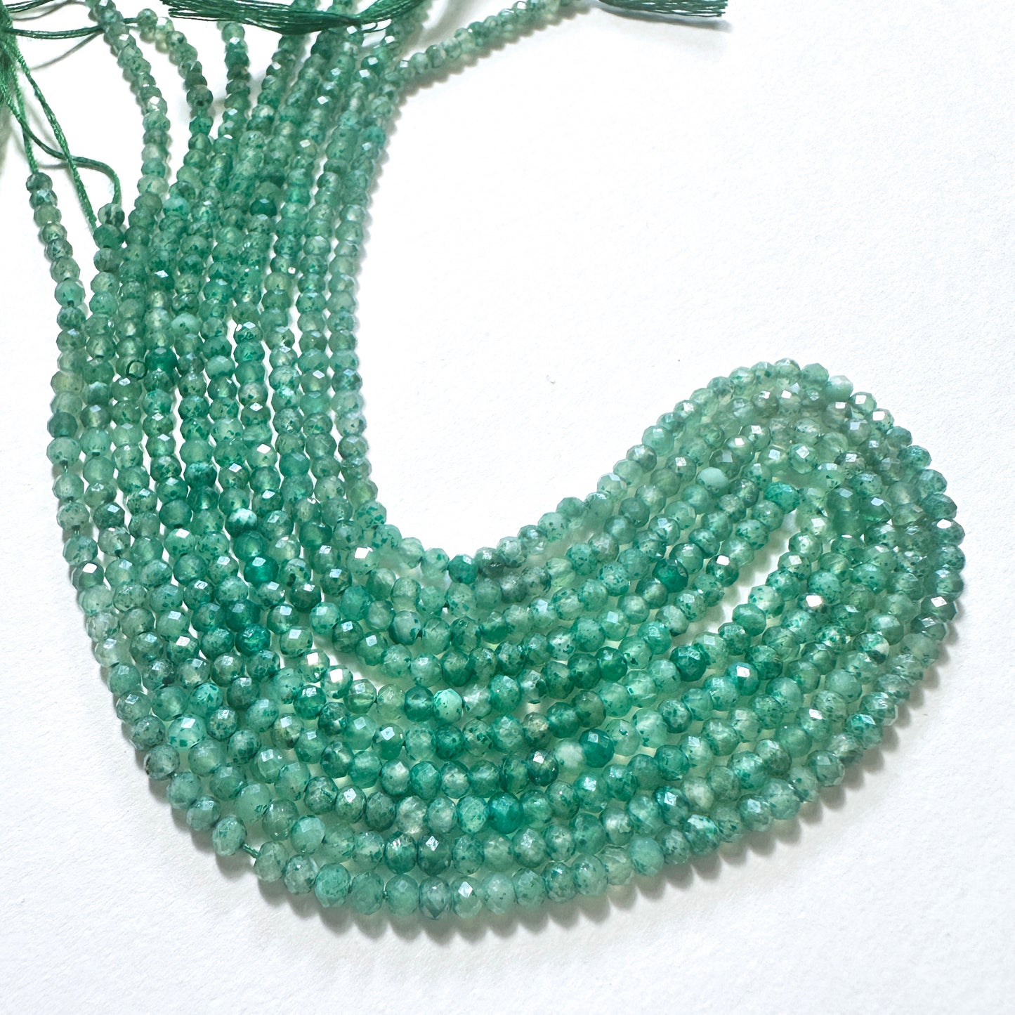 Natural gemstone beads in deep green hues, arranged in neat strands for DIY jewellery making.