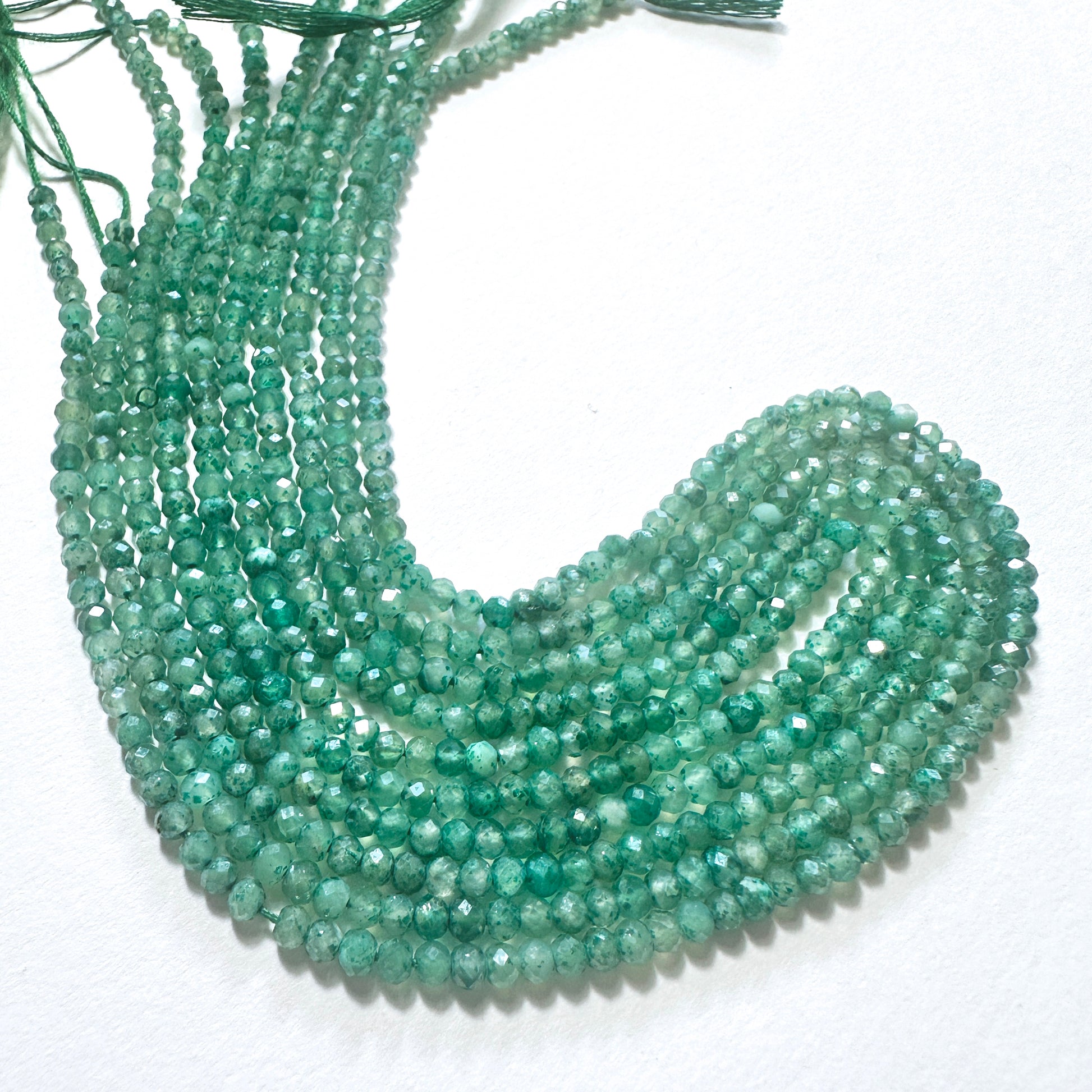 Natural gemstone beads in deep green hues, arranged in neat strands for DIY jewellery making.