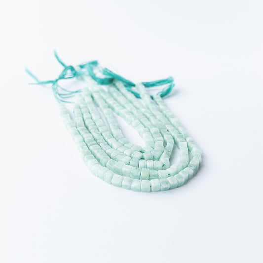 Handmade jewellery components featuring smooth Amazonite cube beads in a neatly arranged strand.
