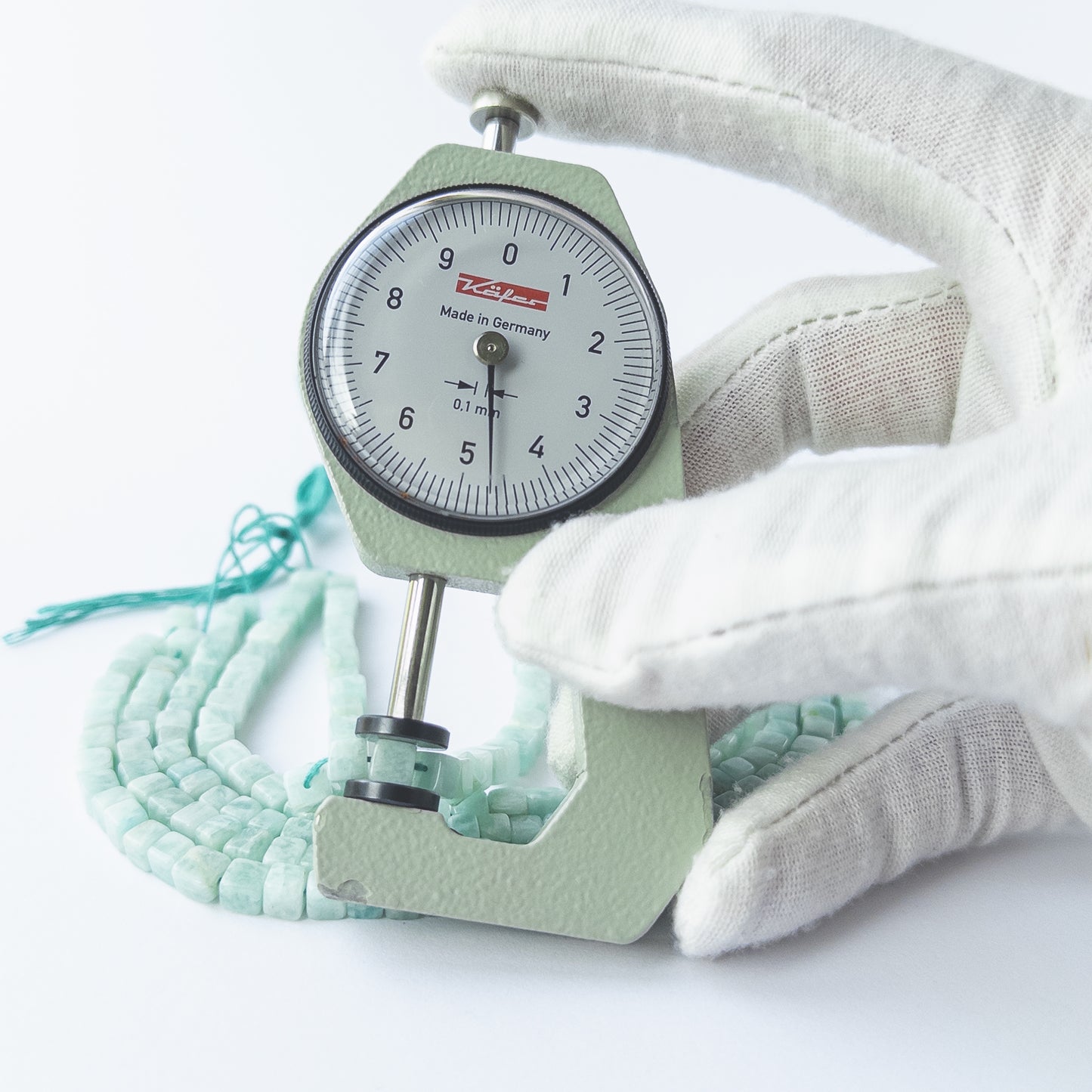 A dial gauge measures the Amazonite smooth cube 4–4.7mm gemstone.