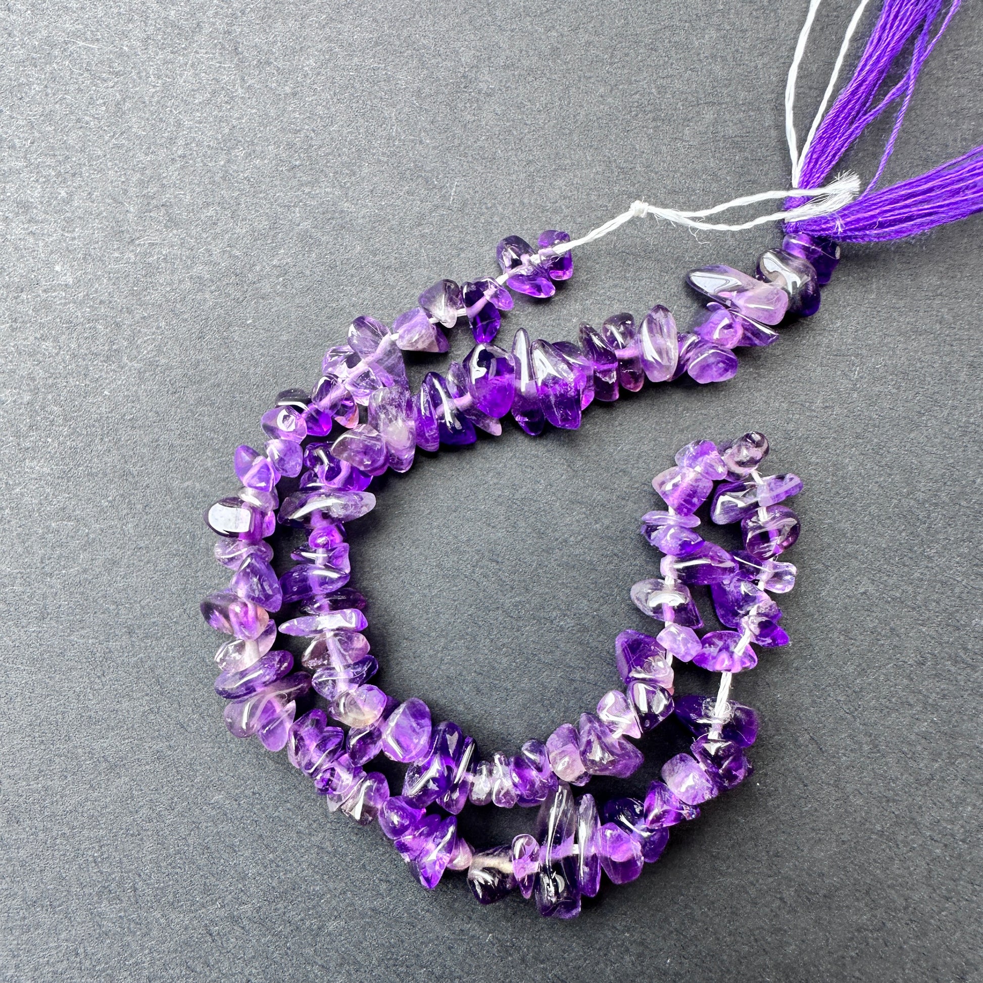 Close-up of Amethyst stone beads showing smooth chip cut and natural gemstone texture.