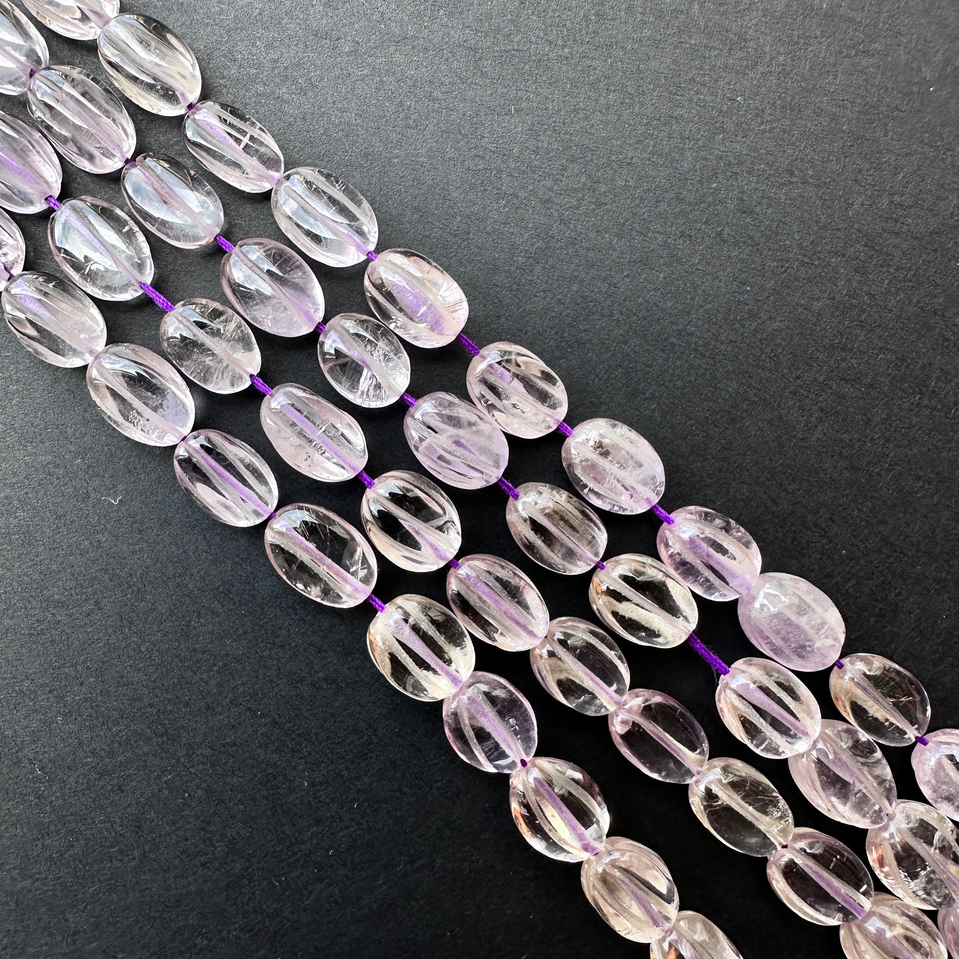 Handmade jewellery components with carved amethyst oval beads in varying sizes and glossy shine.