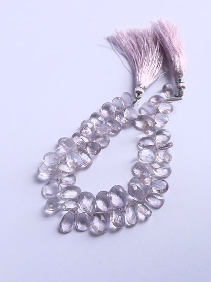 Close-up of natural gemstone beads showing the faceted briolette cut and vibrant Amethyst colour.