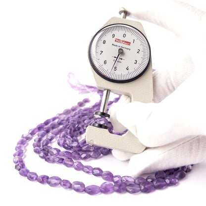 A dial gauge measures the Amethyst faceted rondelle 3.7mm bead size gemstone.