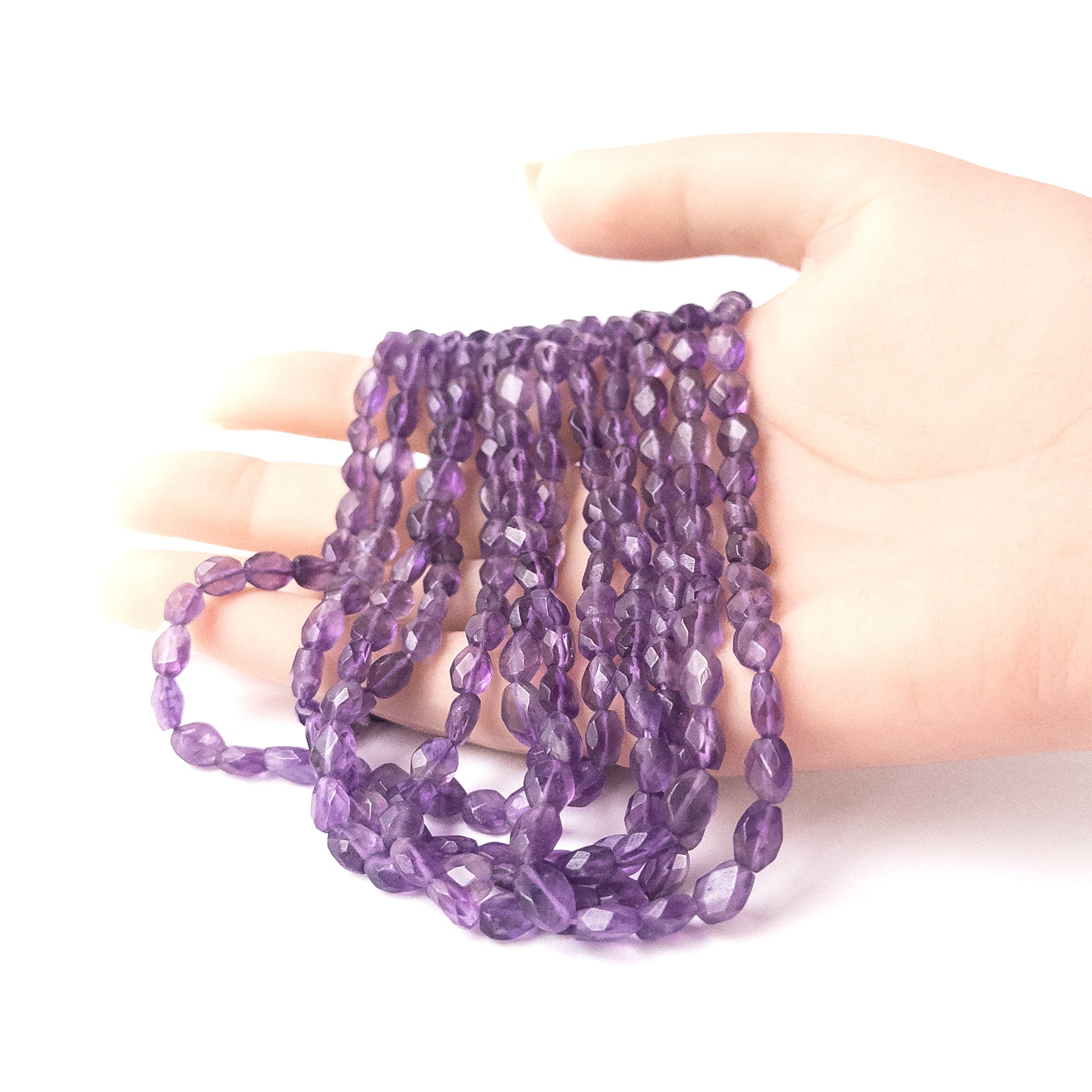 A person holds delicate strands of Amethyst beads, showcasing their faceted rondelle design.