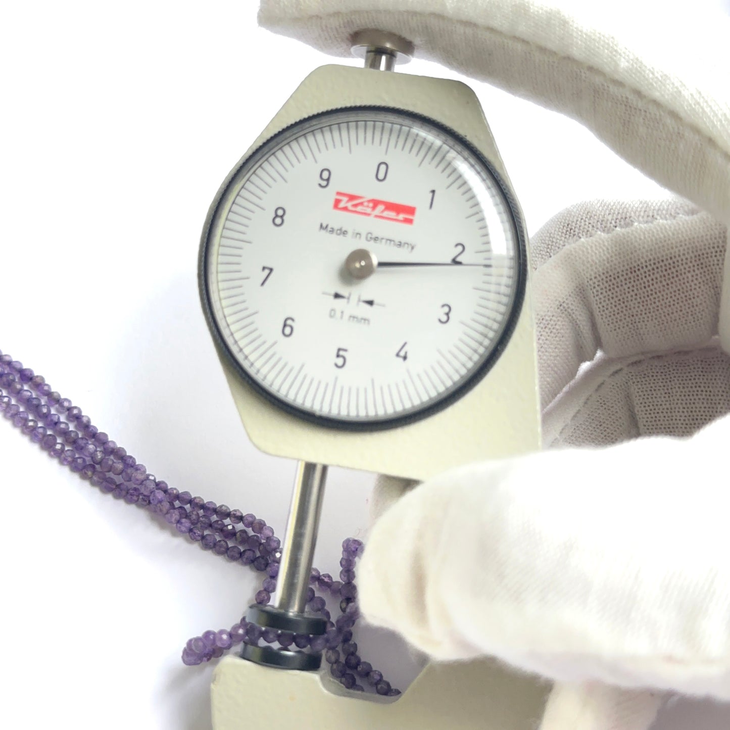 A dial gauge measures the amethyst faceted rondelle 2.2mm gemstone.