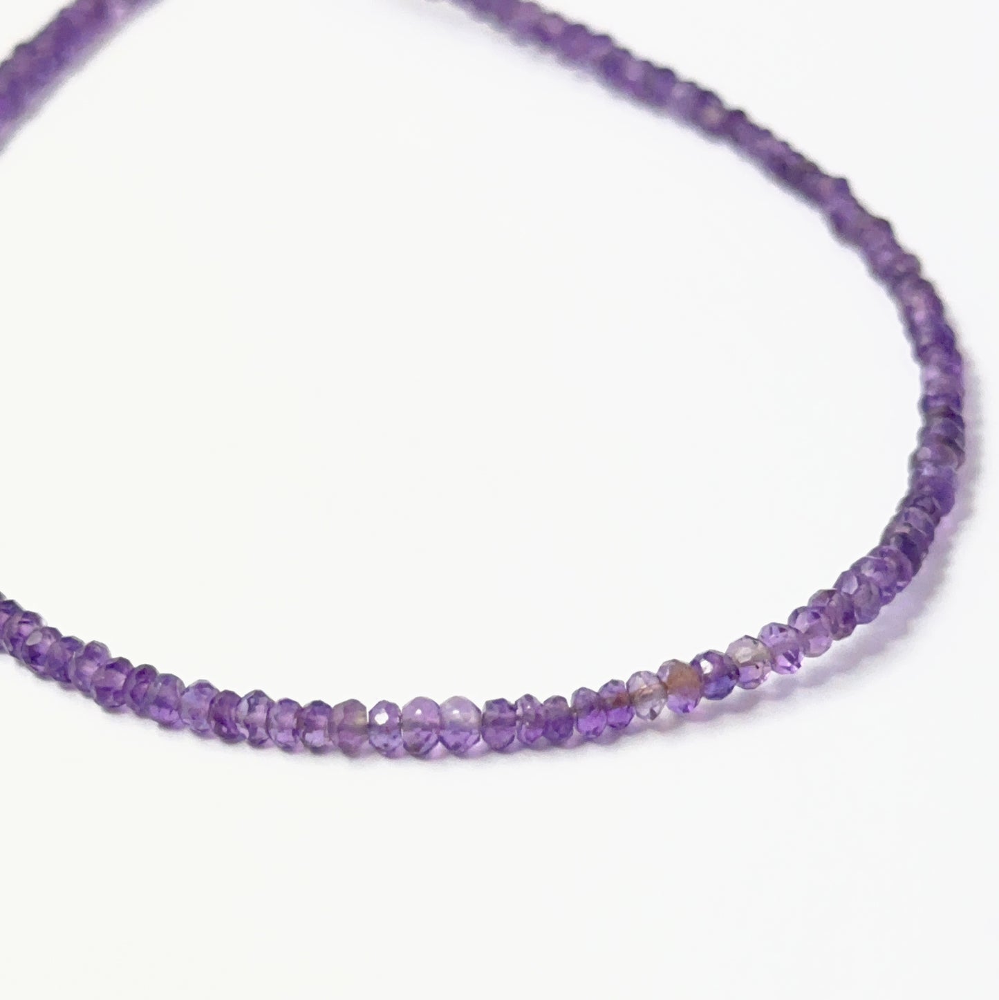 Close view of polished Amethyst faceted rondelles arranged on a 23cm strand for handmade jewellery components.