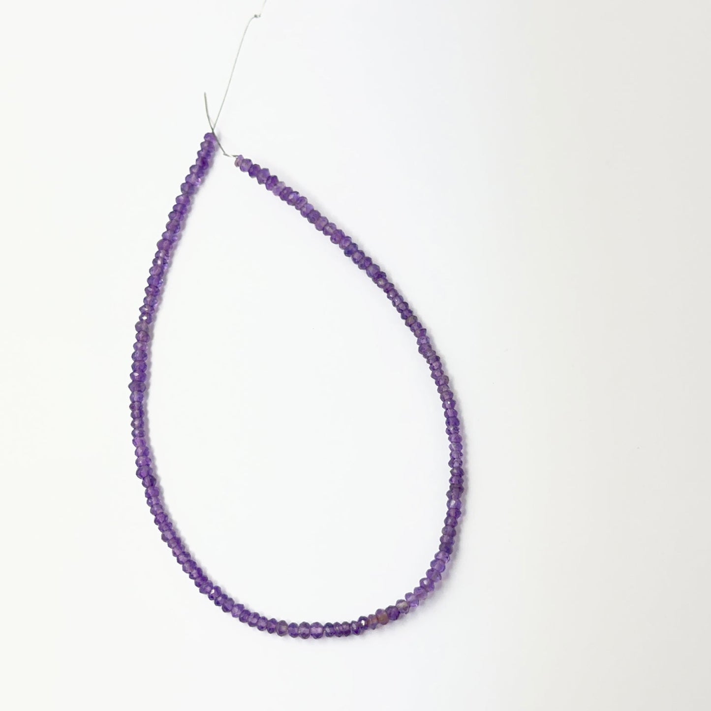 Amethyst faceted rondelle beads aligned on a strand, highlighting clarity, colour and quality stone beads.
