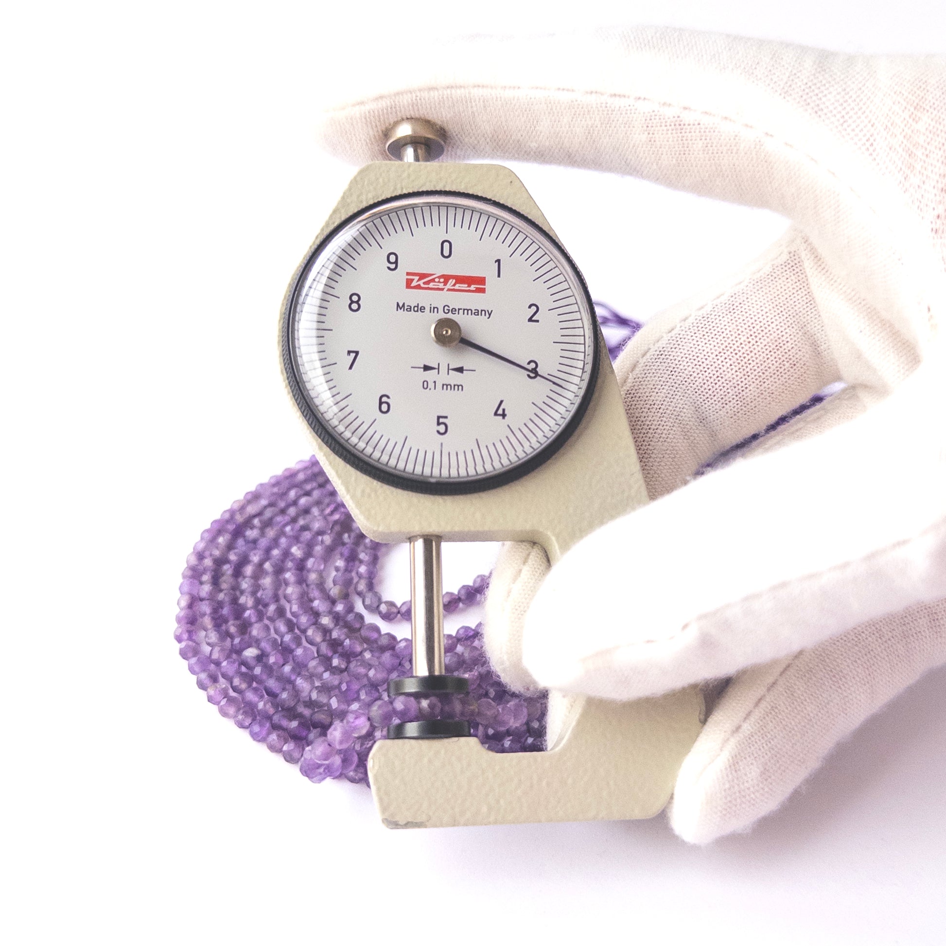 A dial gauge measures the Amethyst faceted rondelle 3.2mm gemstone bead.