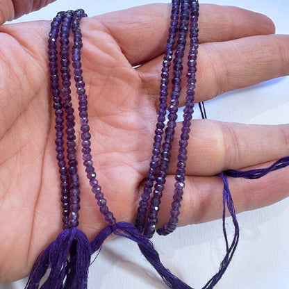 A person holds delicate strands of amethyst beads, showcasing their smooth design.
