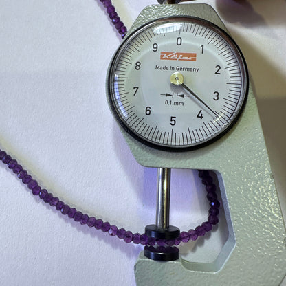 A dial gauge measures the amethyst faceted rondelle 3.5mm gemstone for accuracy.