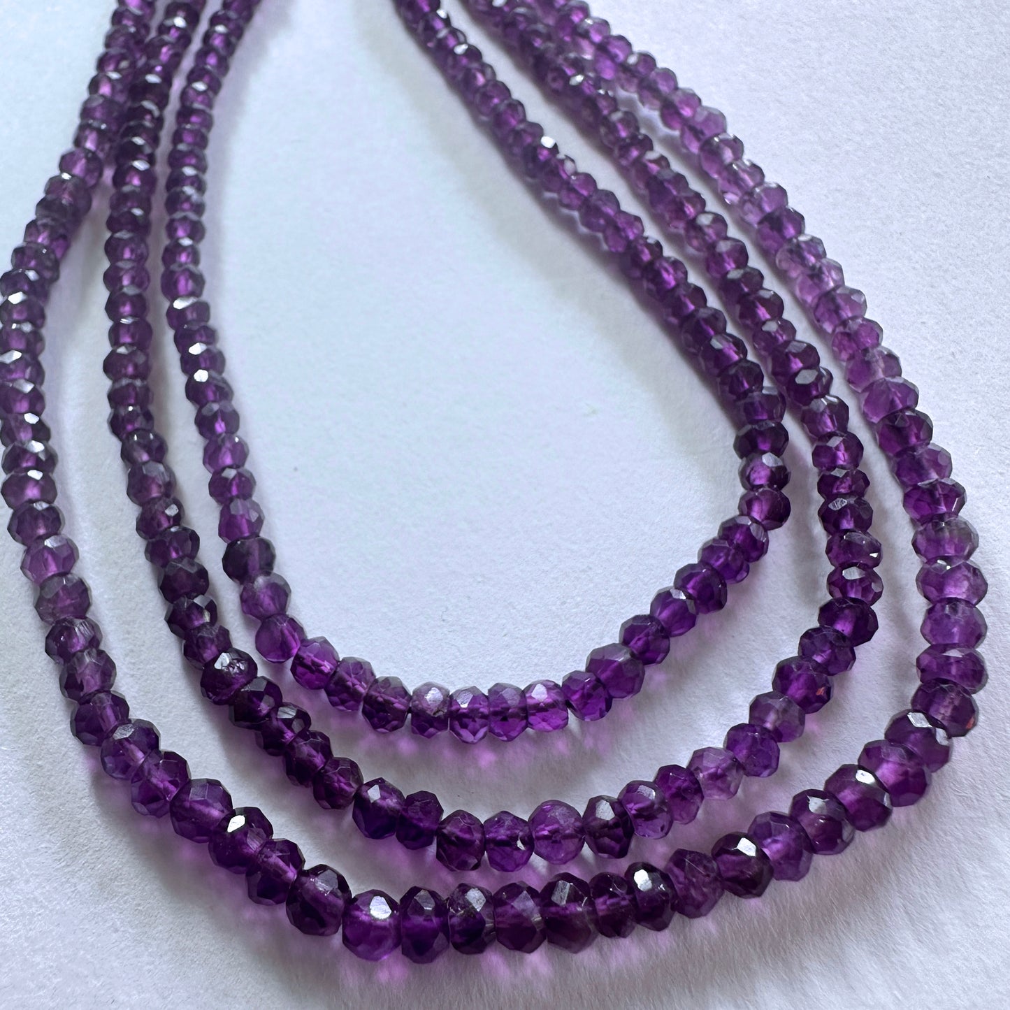 Amethyst gemstone beads in faceted rondelle cut reflect light beautifully across the strand.