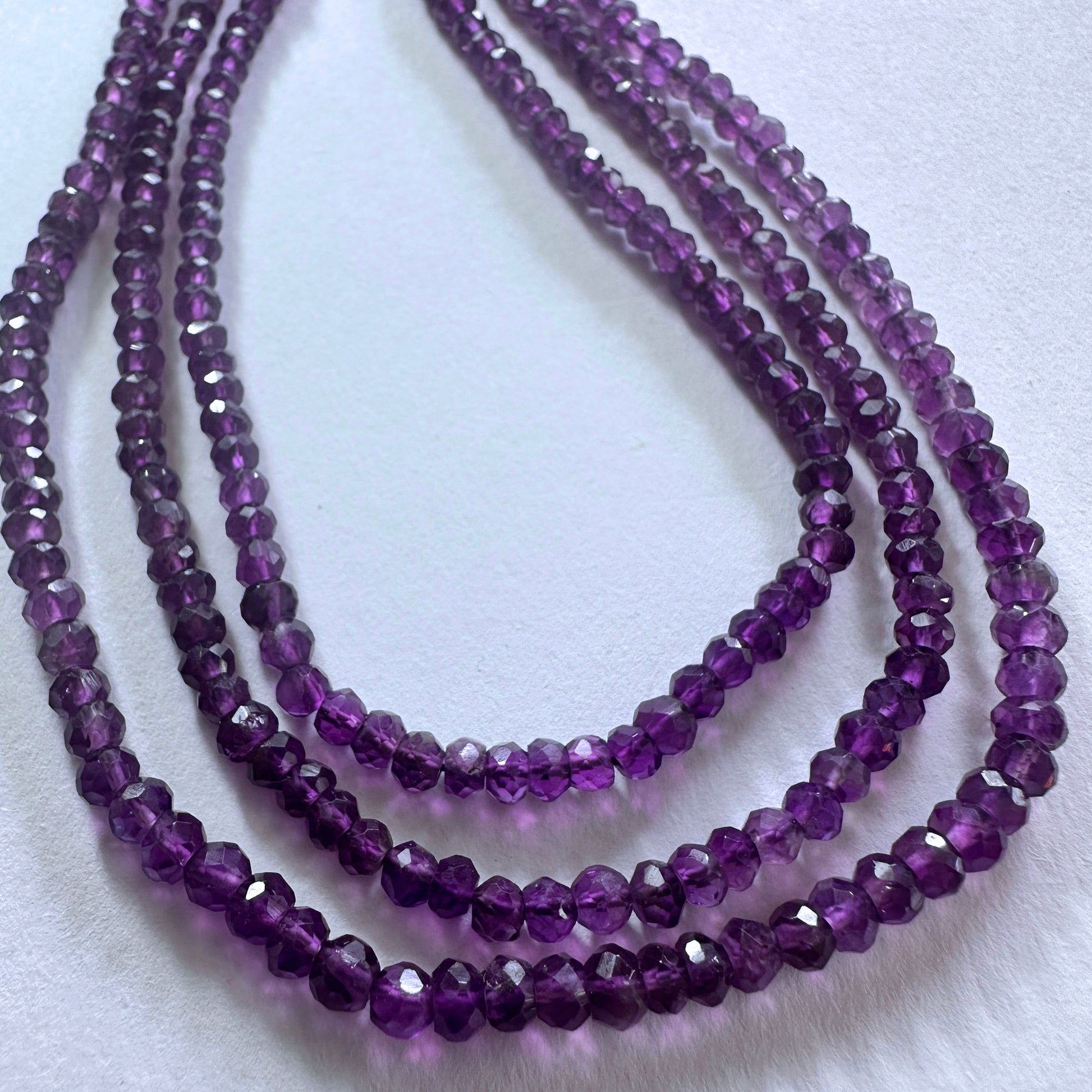 Amethyst gemstone beads in faceted rondelle cut reflect light beautifully across the strand.