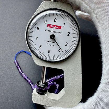 A dial gauge measures the Amethyst faceted rondelle 3.7mm gemstone.