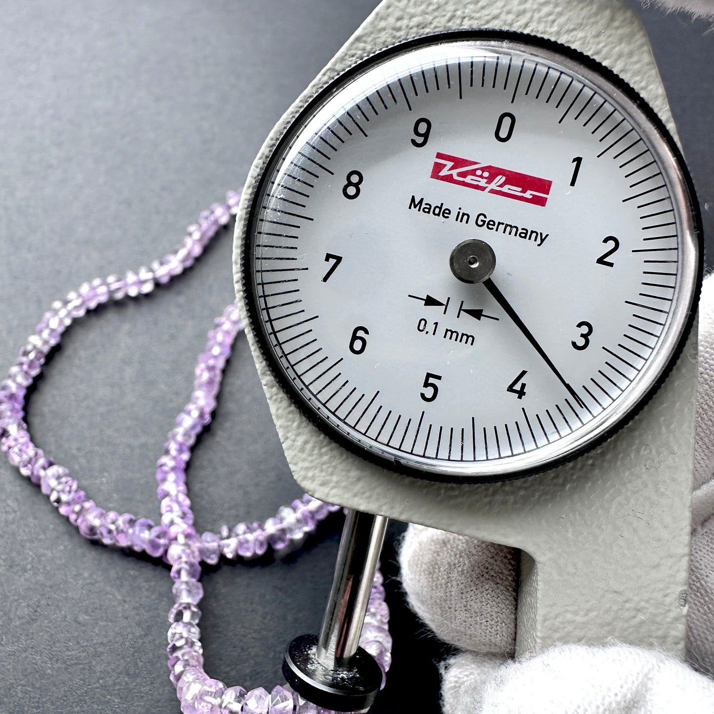 A dial gauge measures the Amethyst faceted rondelle 3.8-4mm gemstone.