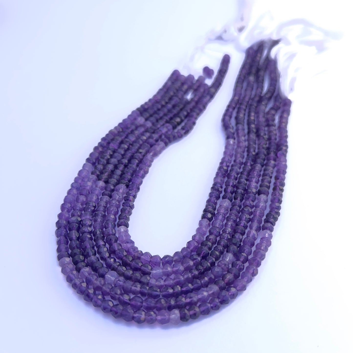 Natural Amethyst stone beads arranged in strands with vibrant purple shimmer.