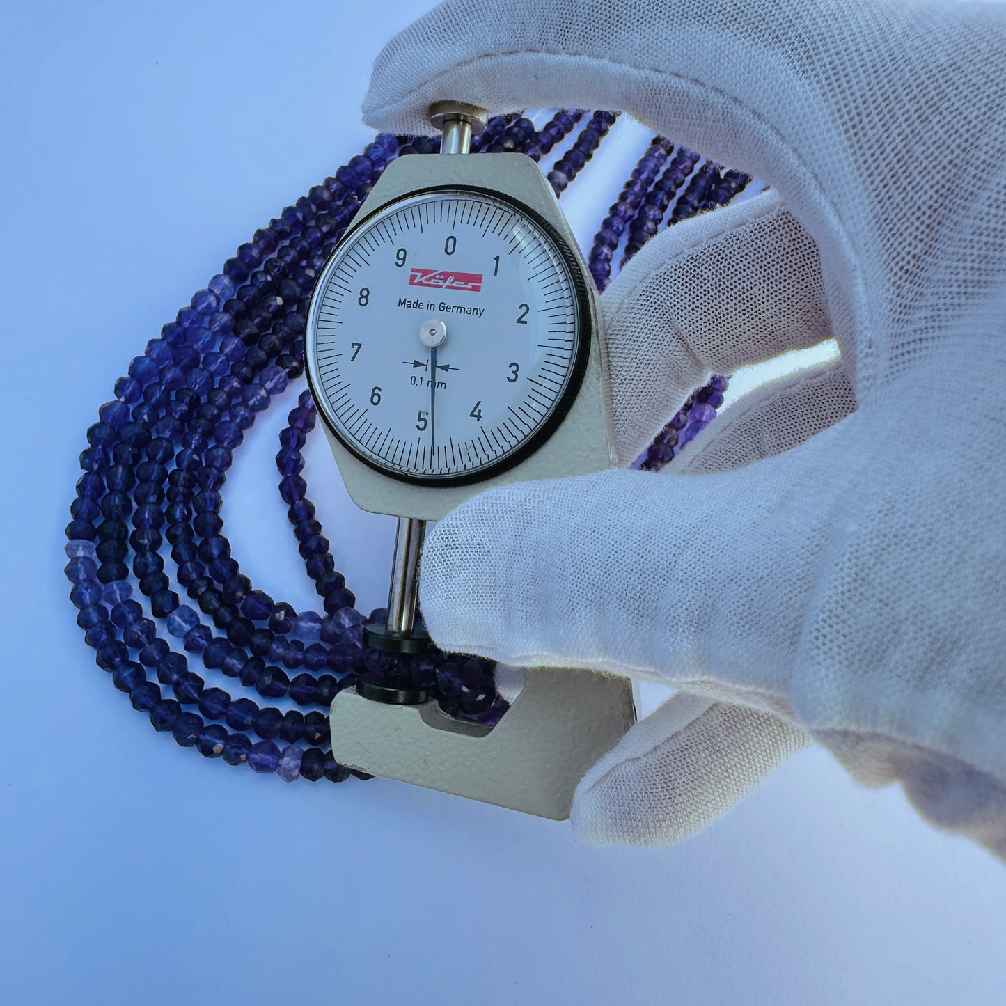A dial gauge measures the Amethyst faceted rondelle 4.5–5mm gemstone.