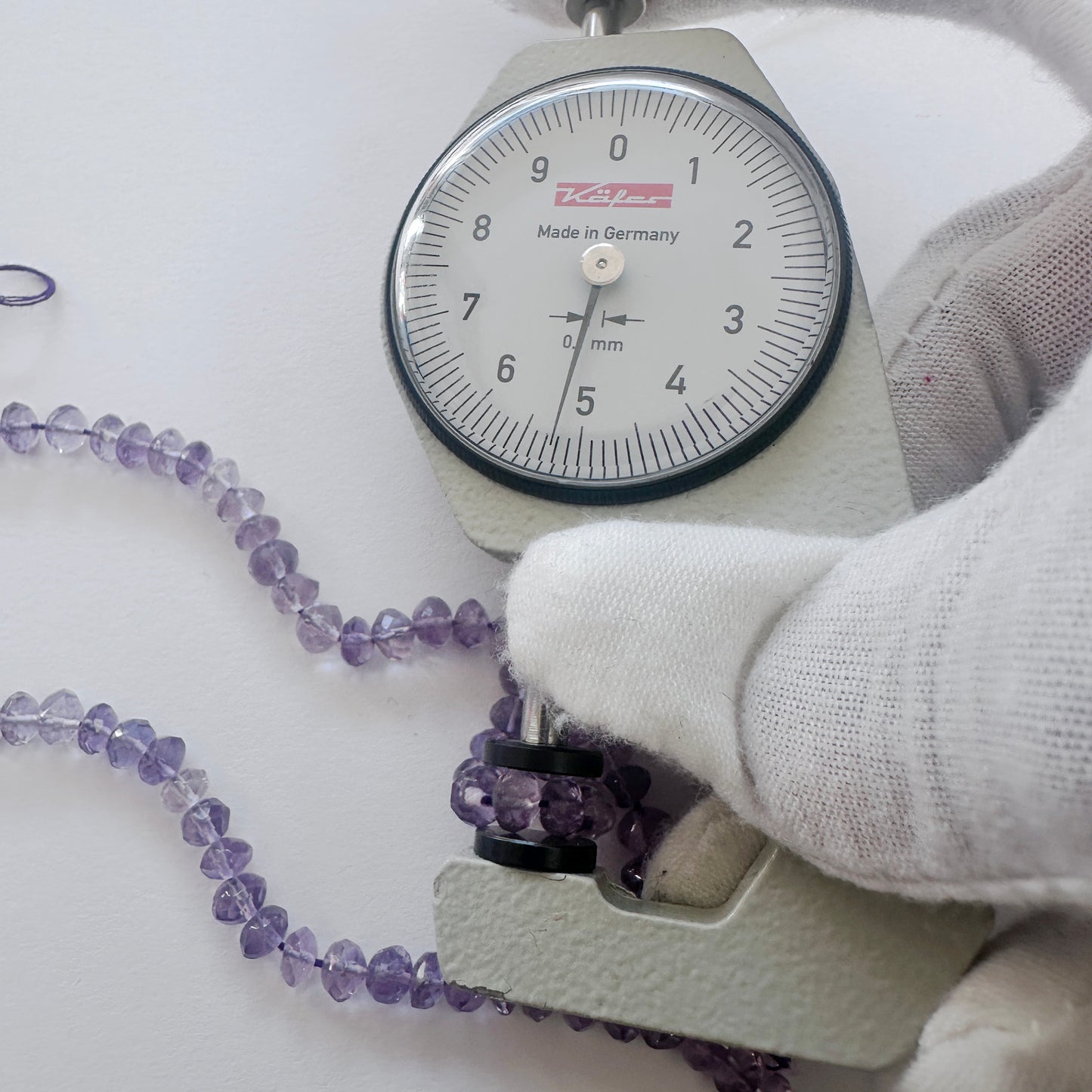A dial gauge measures the Amethyst faceted rondelle 5-5.2mm gemstone.