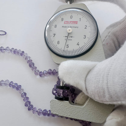 A dial gauge measures the Amethyst faceted rondelle 5-5.2mm gemstone.