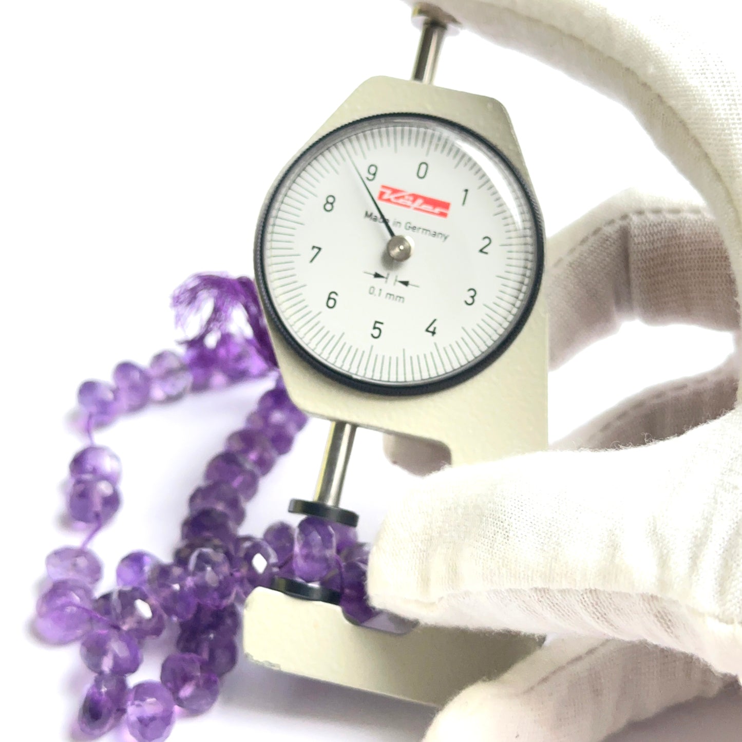 A dial gauge measures the amethyst faceted rondelle 8.5–9.5mm gemstone.