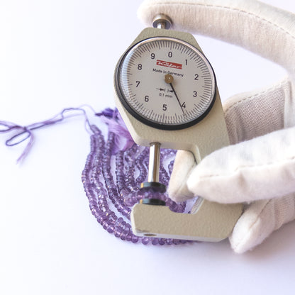 A dial gauge measures the Amethyst faceted rondelle 3–4.3mm gemstone.