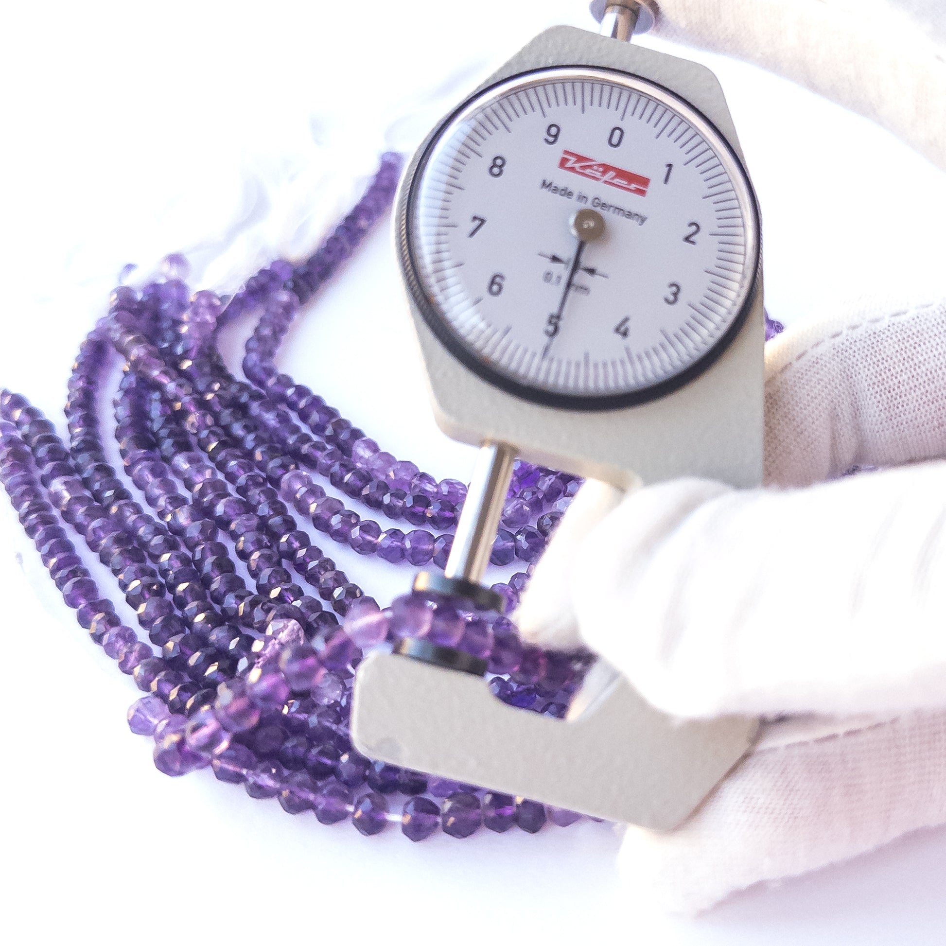 A dial gauge measures the Amethyst faceted rondelle 4.5–5mm gemstone.