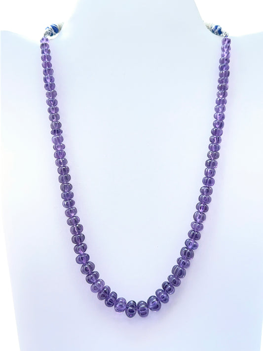 Close‑up of carved amethyst pumpkin beads arranged on a finished necklace.