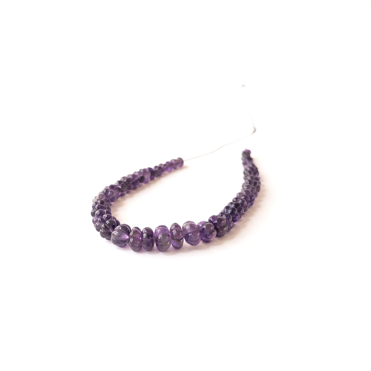 Authentic Amethyst gemstone beads displaying rich purple tones and carved pumpkin‑style detailing.