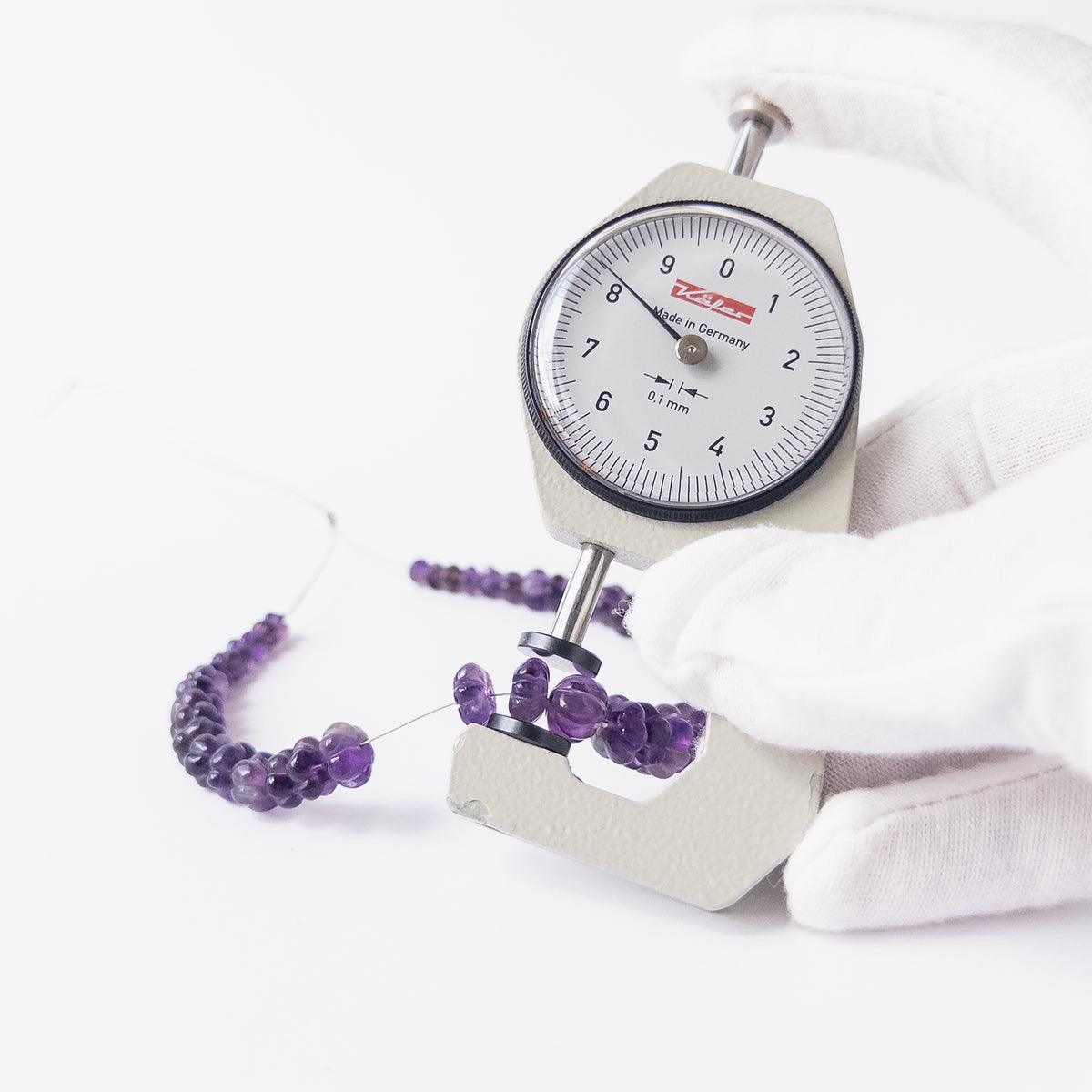A dial gauge measures the Amethyst pumpkin cut 4.5–9mm gemstone.