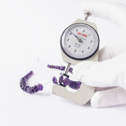 A dial gauge measures the Amethyst pumpkin cut 4.5–9mm gemstone.