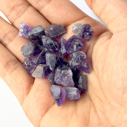 A person holds delicate pieces of Amethyst rough, showcasing their natural rough design.