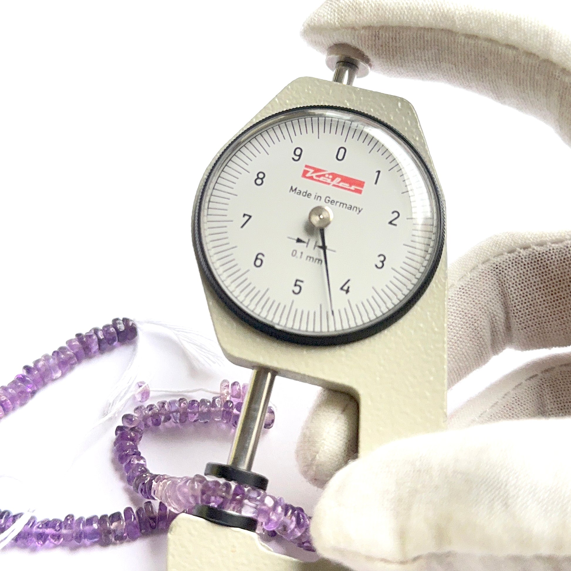 A dial gauge measures the amethyst smooth heishi 4.8-5mm gemstone.