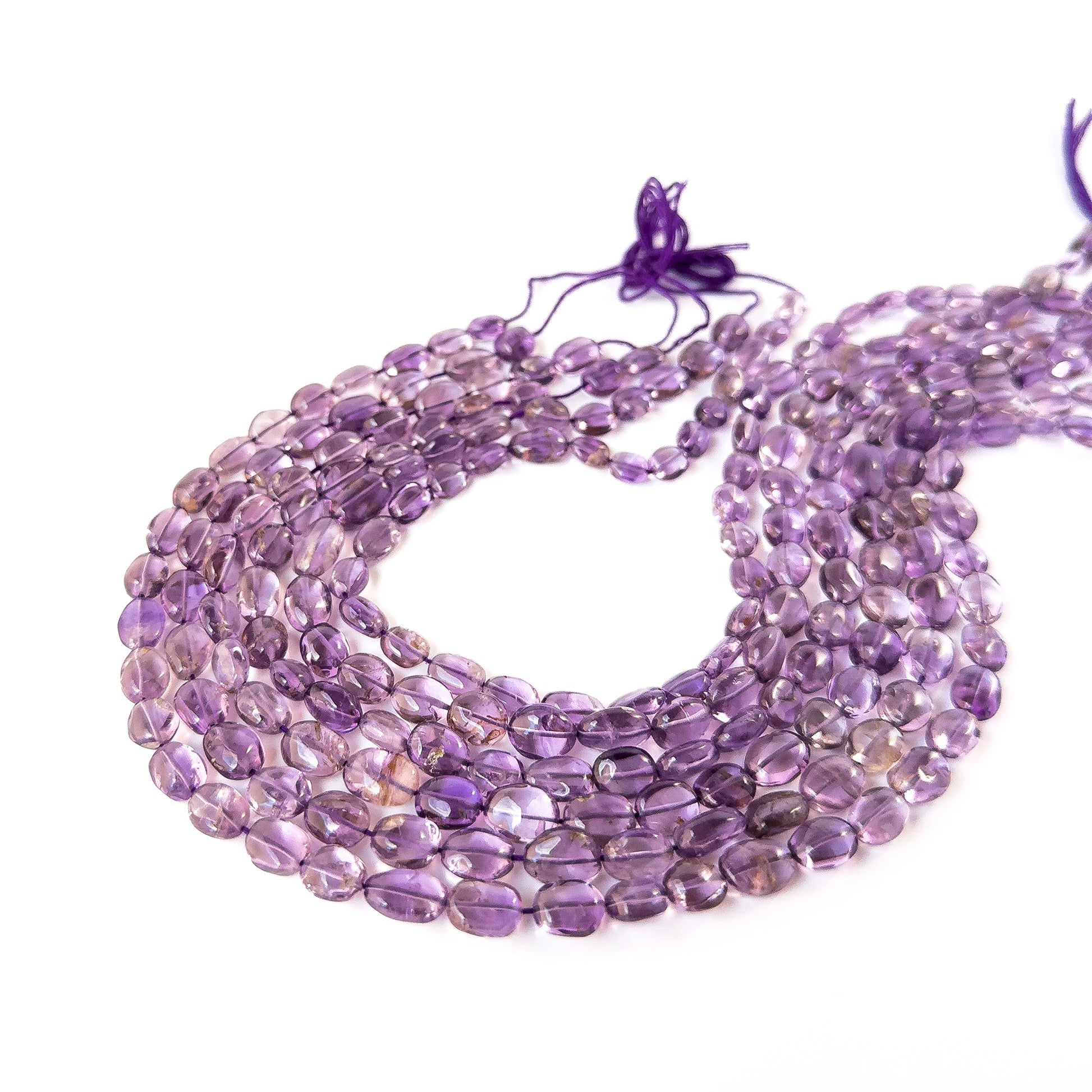 Amethyst smooth oval gemstone beads in soft purple tones arranged on a strand for handmade jewellery components.