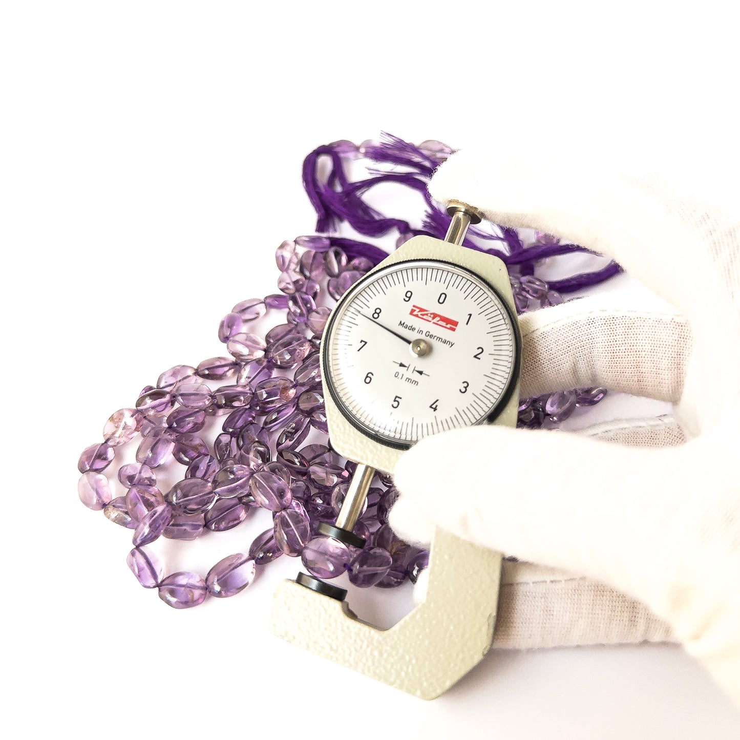 A dial gauge measures the Amethyst smooth oval 6.5–7mm or 7–8mm gemstone.